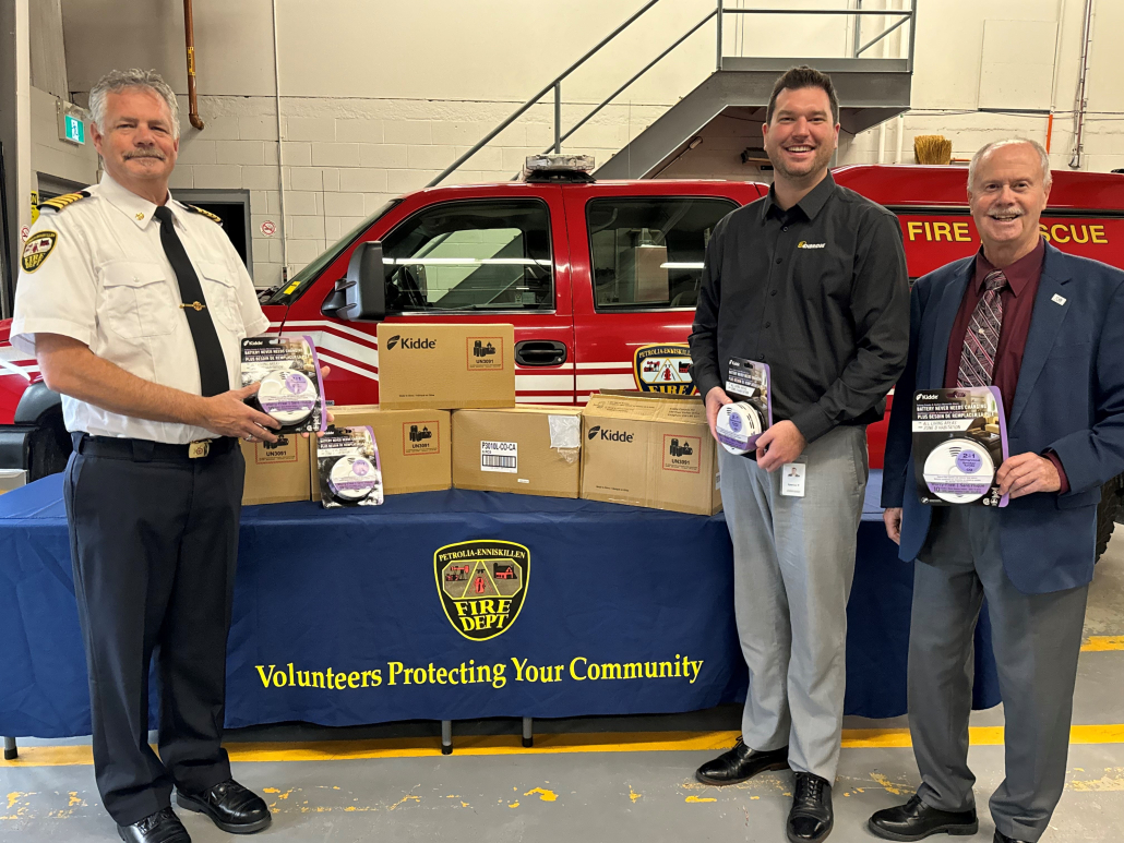 Three individuals with smoke detectors.